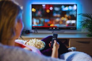 Una ragazza con popcorn e telecomando guarda un film