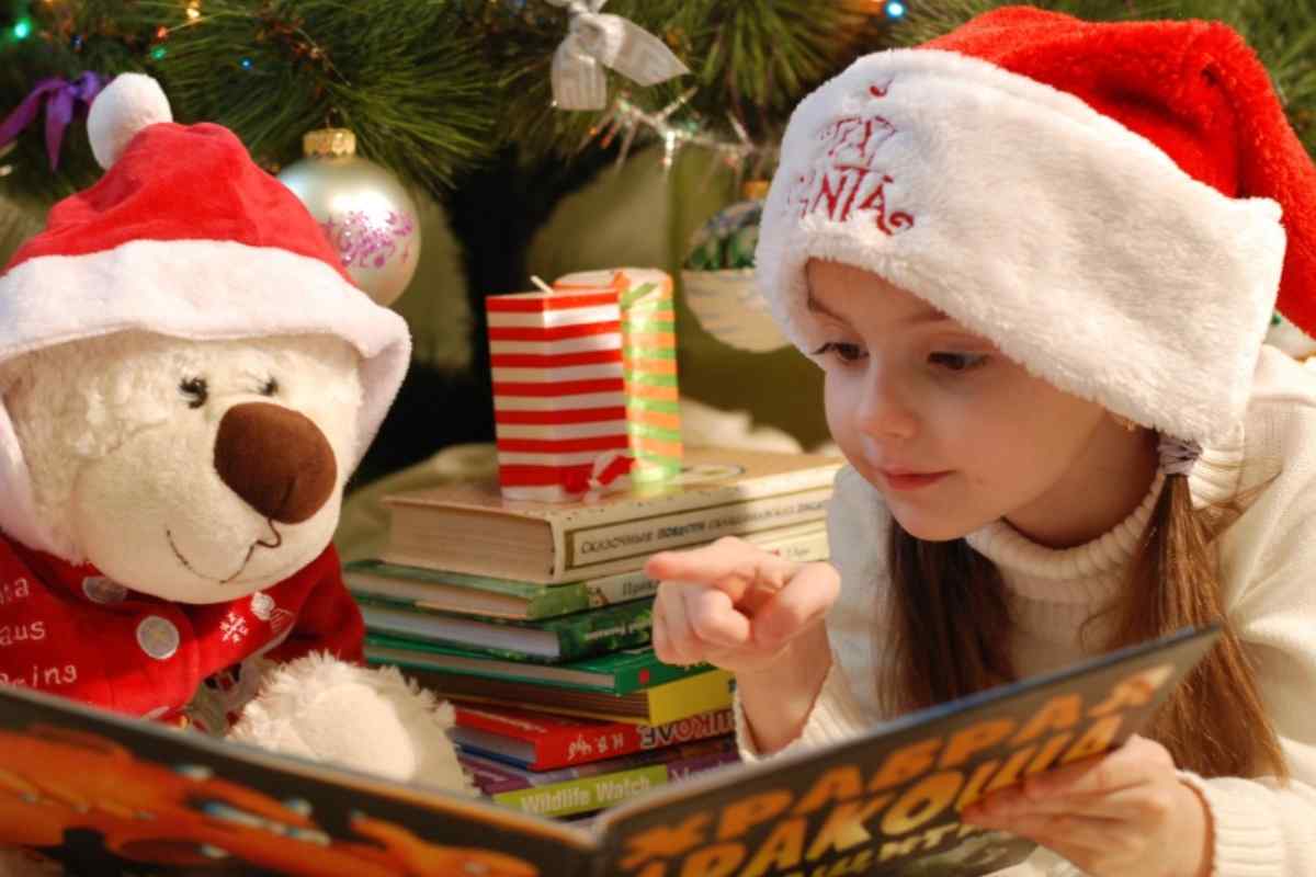 Bambina legge un libro con il suo peluche