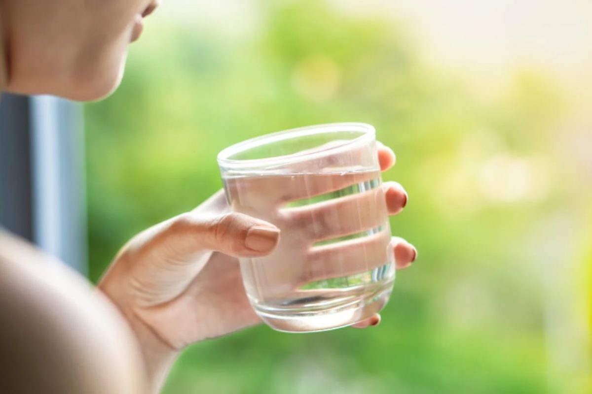 Donna beve un bicchiere d'acqua 